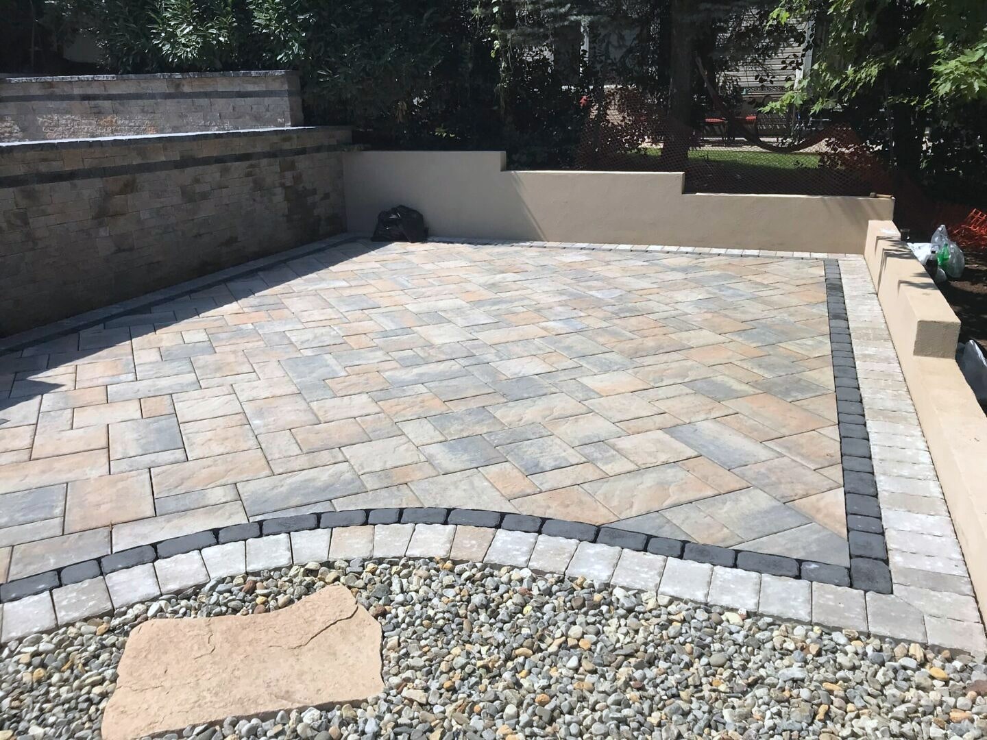 Paver patio with border and gravel edge beside retaining walls
